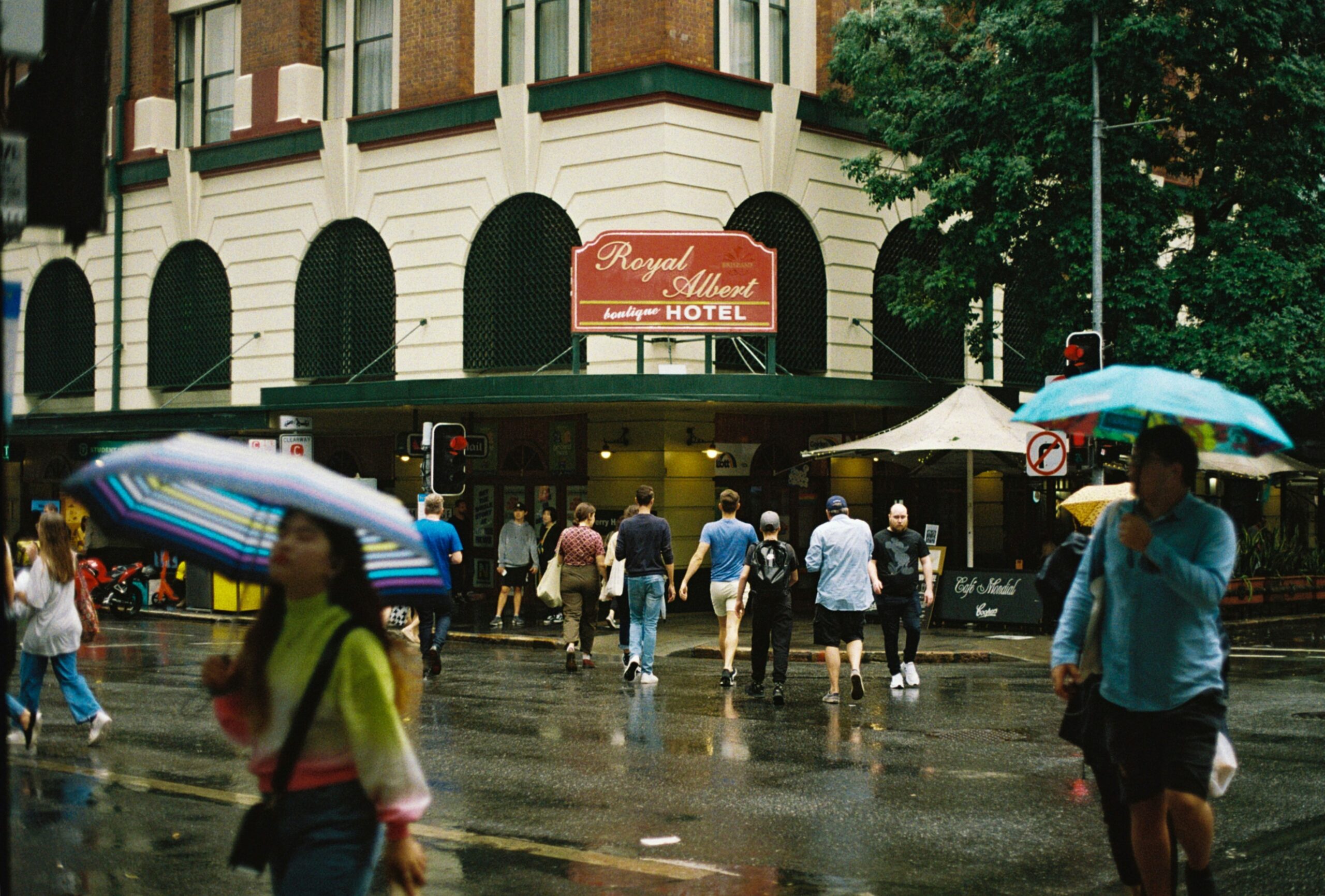 A traveler wearing a hooded rain poncho during a heavy downpour in a vibrant street market.