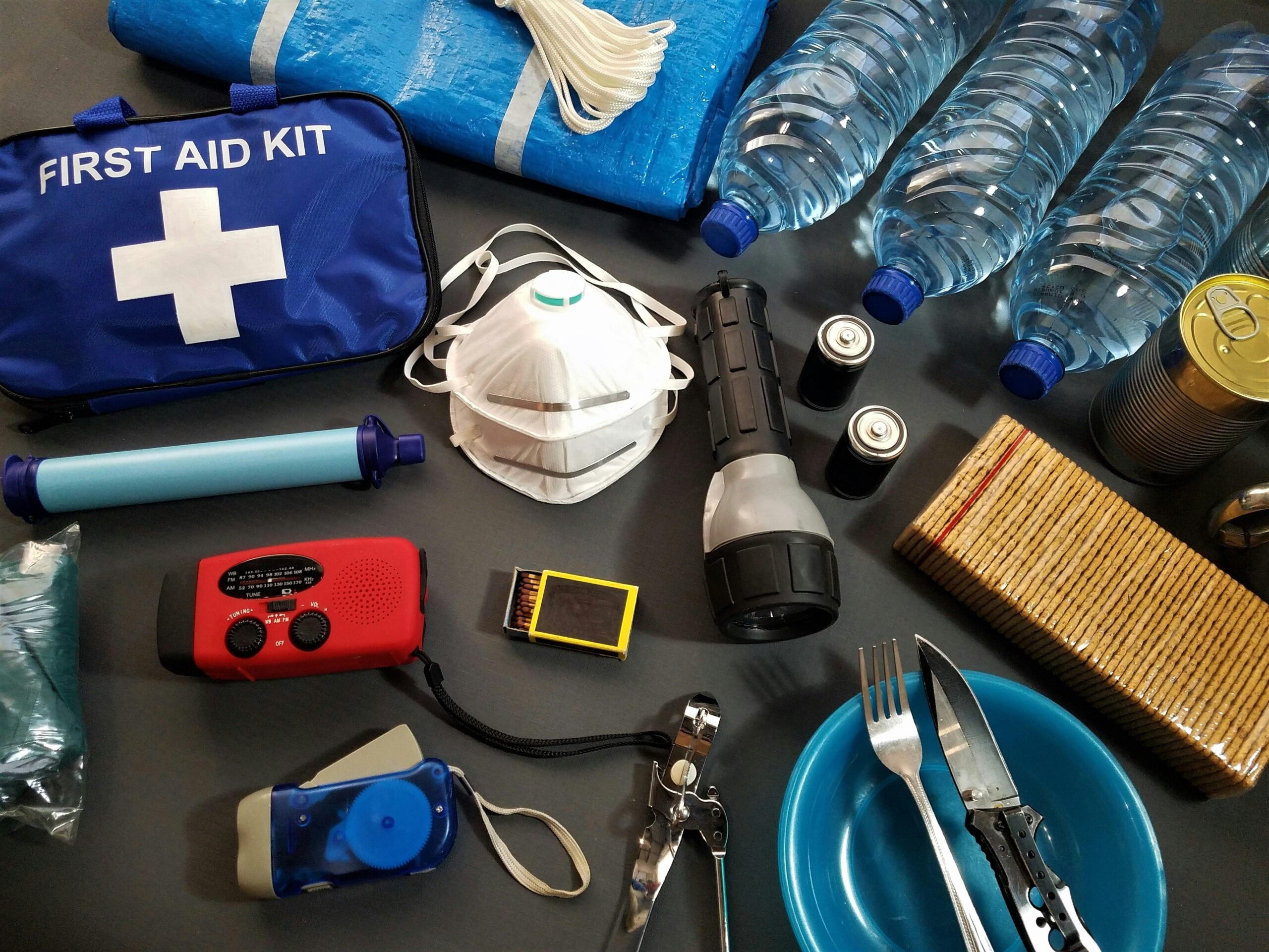 Detailed photo showing layered packing within an emergency kit featuring flashlight, multi-tool, snacks, water purification tablets etc.